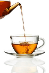 Tea pouring into glass cup isolated in white