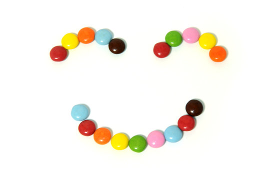 smiley of colorful chocolate candies spread on white background