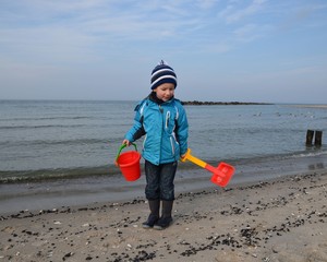Kind mit Eimer und Schaufel am Meer