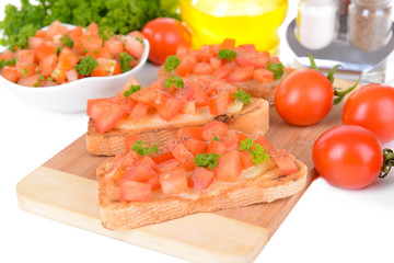 Delicious bruschetta with tomatoes on cutting board close-up