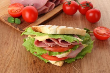 Tasty sandwich with ham on wooden table