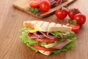 Tasty sandwich with ham on wooden table