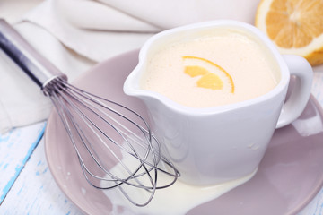 Delicate sauce in pitcher on wooden table close-up