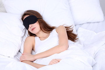 Obraz na płótnie Canvas Young beautiful woman sleeping in bed with eye mask close-up