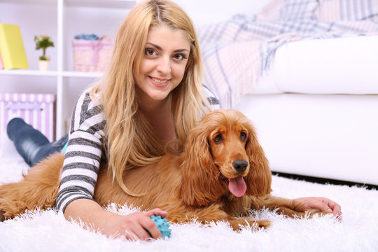 Beautiful young woman with cocker spaniel in room