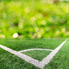 Naklejka premium Corner of a soccer field and green bokeh