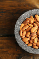 Almonds in bowl on color wooden background