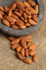 Almonds in bowl on sackcloth background