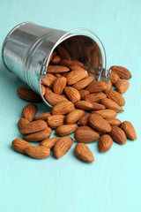 Almonds in bucket on color wooden background