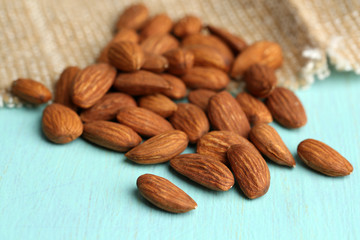 Almonds on color wooden table, on sackcloth background