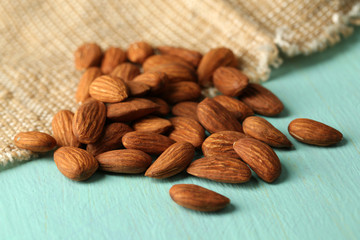Almonds on color wooden table, on sackcloth background