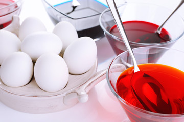 Eggs with liquid colour in glass bowls close up