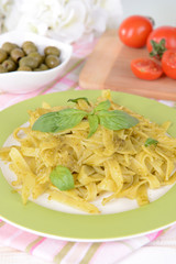 Delicious pasta with pesto on plate on table close-up