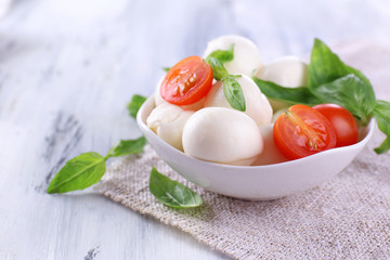 Tasty mozzarella cheese with basil and tomatoes in bowl,