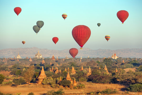 Hot air balloons over Buddhist temples at sunrise. Bagan.