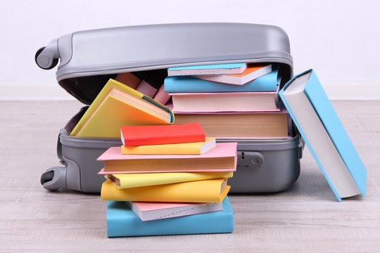 Books in suitcase on wall background