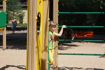Dziewczynka na placu zabaw obok drabinek.