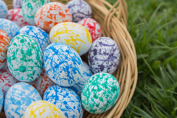 Colorful Easter eggs in a Wicker basket, On the grass