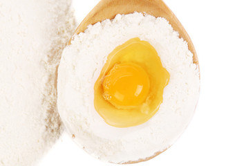 Egg with flour in a wooden spoon.
