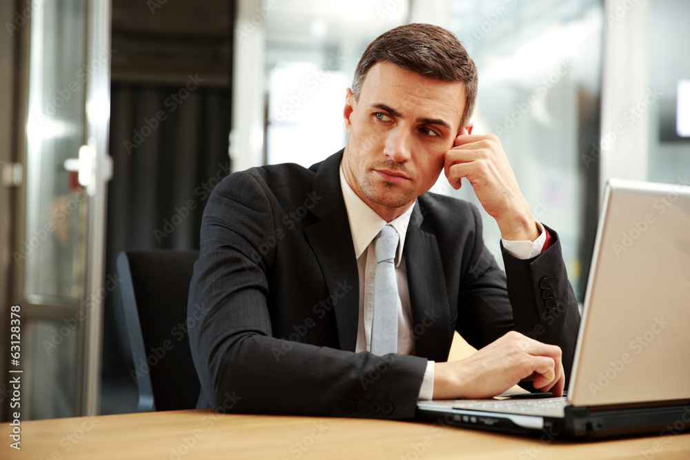 Poster Pensive businessman sitting with laptop at office