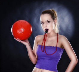 female football supporter with whistle and football ball, studio