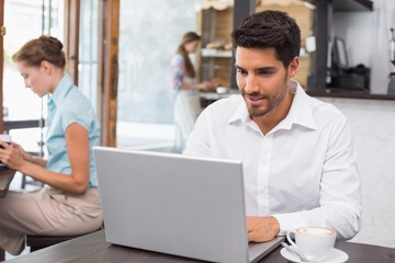 Fototapeta premium Concentrated man using laptop in coffee shop