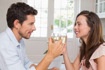 Loving couple toasting wine glasses at home
