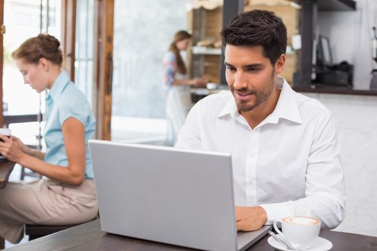 Concentrated man using laptop in coffee shop
