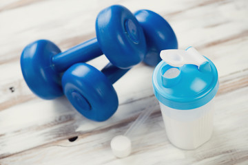 Protein shake with plastic dumbbells and a measuring scoop