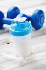 Shaker with whey protein and plastic dumbbells, vertical shot