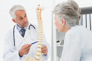 Male doctor explaining the spine to senior patient