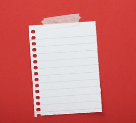 Piece of lined paper taped to a red background with copy space