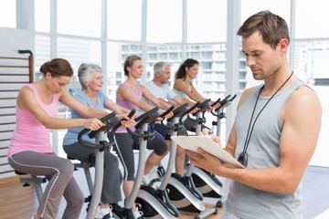 Trainer with people working out at spinning class