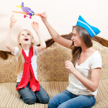 Beautiful sisters playing with toy airplane at home