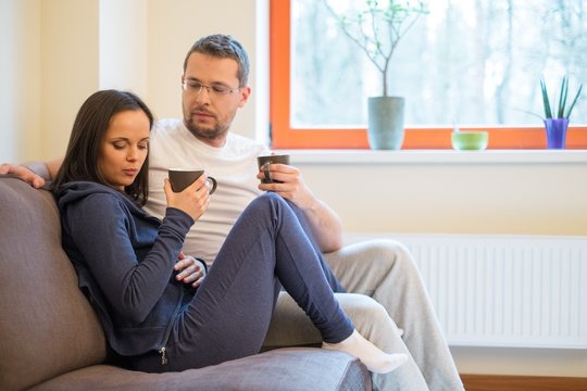 Young Pensive Couple On A Sofa In Home Interior