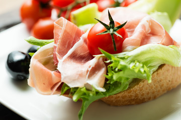 Ham sandwich with tomato and olive on plate