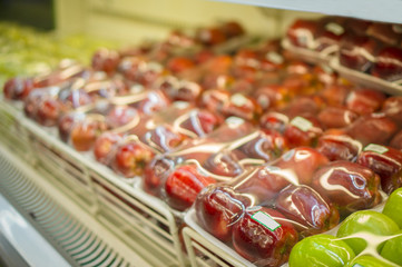Rows of red apples in plastic package on shelf in store
