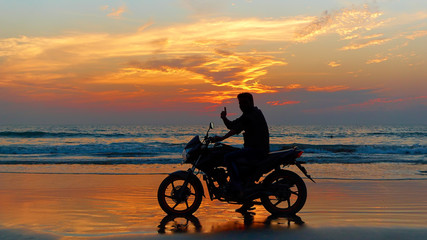 Fototapeta na wymiar Motorcyclist at sunset on the beach.