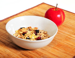 Мюсли в тарелке и яблоко
