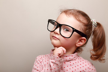 Smart dreaming kid girl in glasses looking