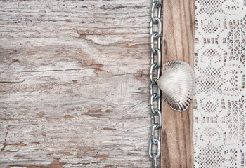 Lace fabric with chain and seashell on the old wood