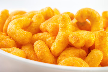 Cheese puff snacks on bowl closeup