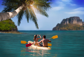 Man and girl kayaking next to a tropical island