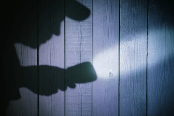 Human silhouette with flashlight in shadow on wood background, X - obrazy, fototapety, plakaty
