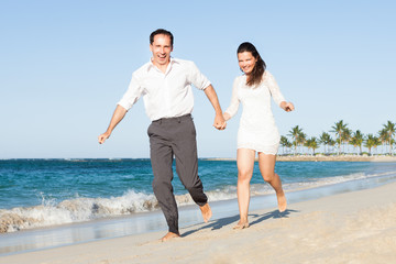 Fototapeta premium Happy Couple Holding Hands While Running On Beach