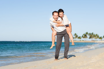 Man Giving Piggyback Ride To Woman At Beach