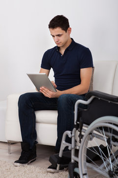Handicapped Man Using Digital Tablet On Sofa