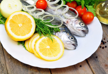 Fototapeta na wymiar two rainbow trout with lemon and fresh vegetables
