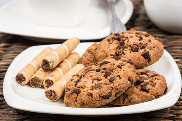 chocolate cookies with wafer rolls next to cup of coffee