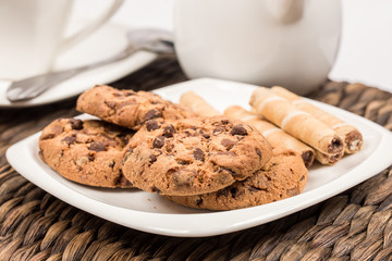 chocolate cookies with wafer rolls next to cup of coffee